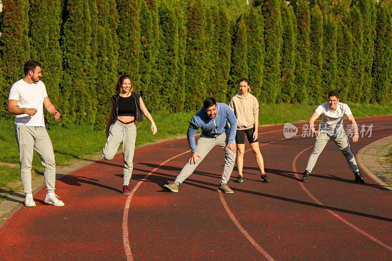 A group of friends preparing to start running on a track in a public park